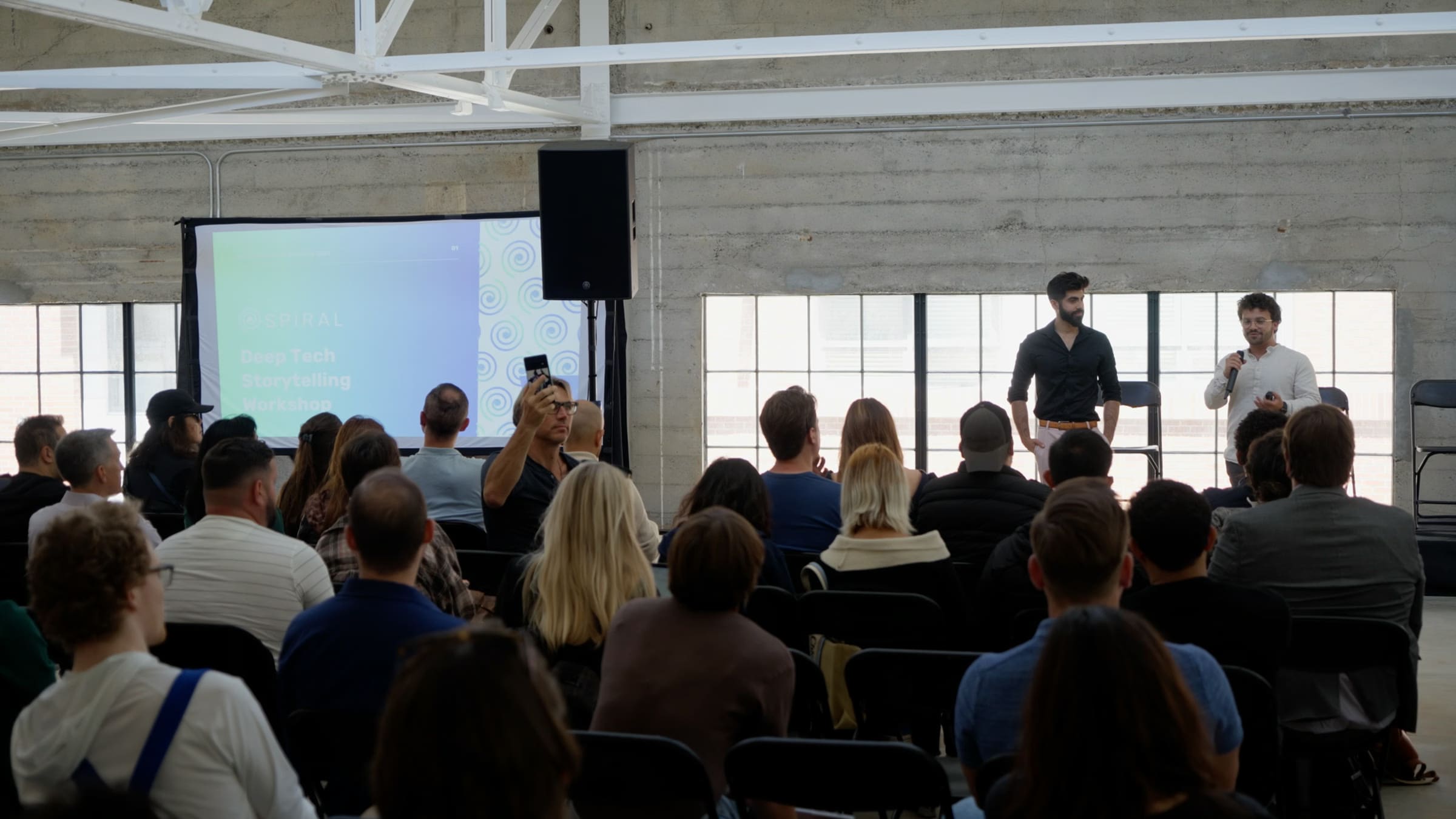 A full room of founders seated for a Spiral Studios storytelling workshop, with the title slide on screen.
